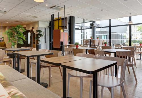 a restaurant with tables and chairs and windows at B&B HOTEL Epernay in Épernay