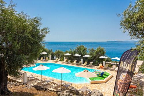 a swimming pool with umbrellas and the ocean at Nissaki Sea View Hotel in Corfu