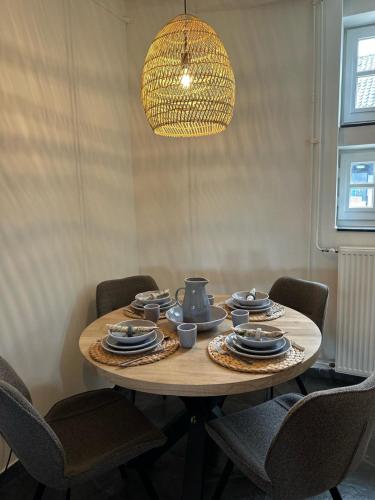 a wooden table with chairs and a chandelier at Authentieke 4 persoons cottage vlakbij Valkenburg in Voerendaal