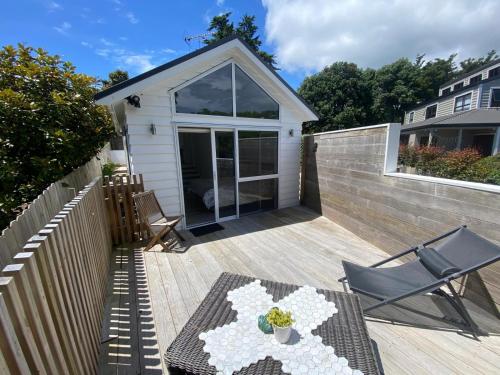 a patio with a table and chairs on a deck at Maraetai -Kererū Cottage - Whole House in Maraetai