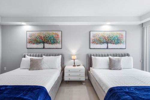 two beds in a bedroom with two paintings on the wall at Solare Tower Sunset Panorama Paradise in South Padre Island
