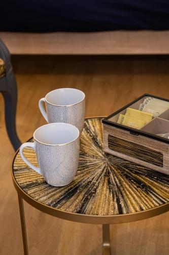 deux tasses à café sur une table en verre avec des livres dans l'établissement Cosy Haven Studio rénové, élégant Pougues les Eaux, à Pougues-les-Eaux