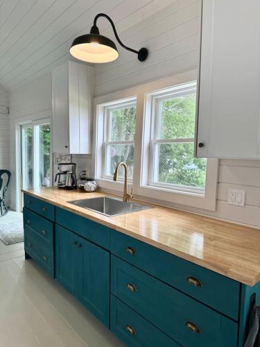 a blue kitchen with a sink and two windows at Eagles Bluff Cottage in Eastport