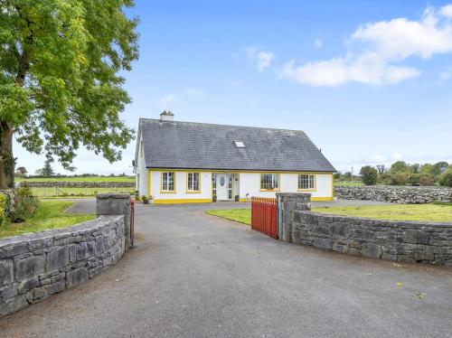 a yellow house with a stone fence in front of it at Lough Mask Fishing Lodge in Ballinrobe