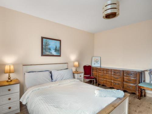 a bedroom with a white bed and a red chair at Lough Mask Fishing Lodge in Ballinrobe