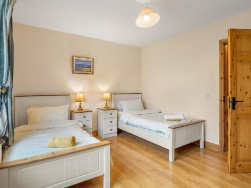 a bedroom with two beds and two lamps and wooden floors at Lough Mask Fishing Lodge in Ballinrobe