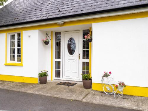 a white house with a yellow door and a bicycle at Lough Mask Fishing Lodge in Ballinrobe