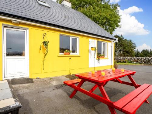 a red picnic table in front of a yellow tiny house at Lough Mask Fishing Lodge in Ballinrobe