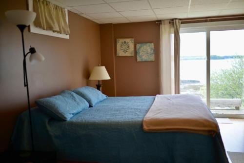a bedroom with a blue bed and a window at Mudges Bluff Waterfront Retreat in Lubec
