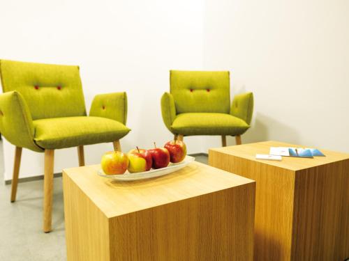 two green chairs and a plate of apples on a table at Ferienhotel Bodensee in Berlingen