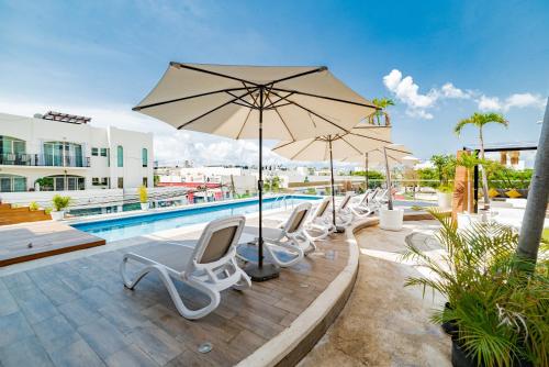 a group of chairs and umbrellas next to a pool at Cache Hotel Boutique - Adults Only in Playa del Carmen