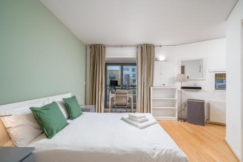 a bedroom with a large white bed with green pillows at Lovely 3BD Flat, Parking, sleeps SIX close to O2 in London