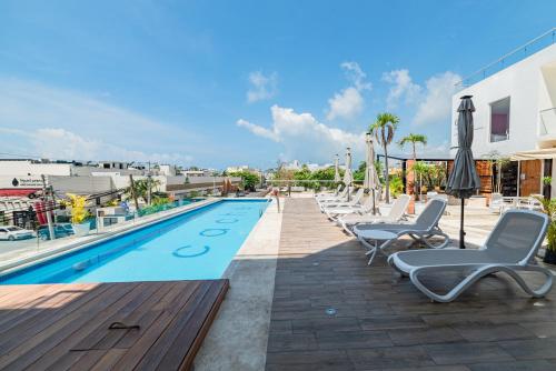 a swimming pool with lounge chairs and umbrellas on a building at Cache Hotel Boutique - Adults Only in Playa del Carmen