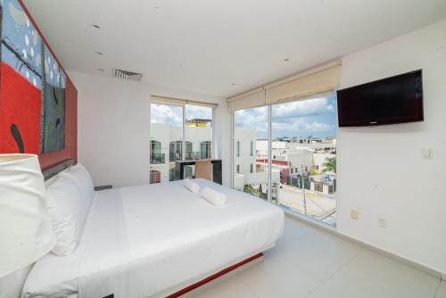 a bedroom with a white bed and a large window at Cache Hotel Boutique - Adults Only in Playa del Carmen