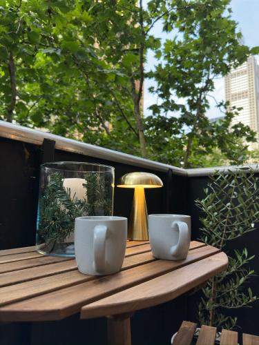 a wooden table with two cups and a lamp on a balcony at Collins Escape - 2 bedrooms with Collins St Balcony in Melbourne