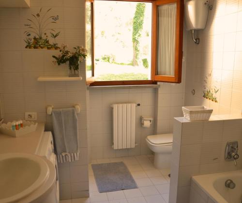 a bathroom with a toilet and a sink and a window at Villa Noemi in Scarlino