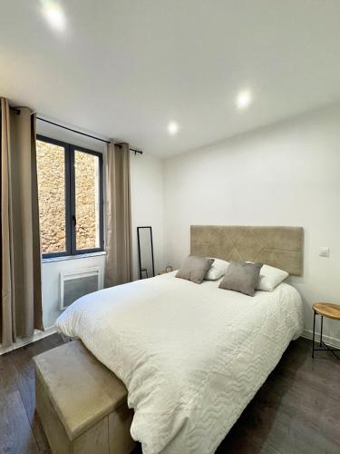 a white bedroom with a large bed and a window at Narbonne centre New york in Narbonne