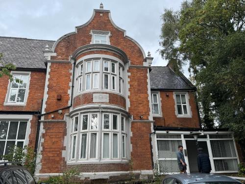 two people standing in front of a brick house at OYO A Better Night Hotel - Manchester Salford in Manchester