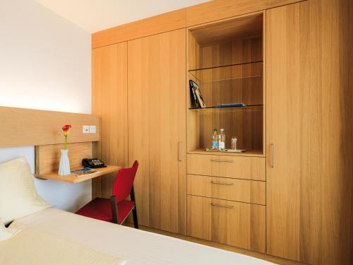 a bedroom with a bed and a desk and a cabinet at Ferienhotel Bodensee in Berlingen