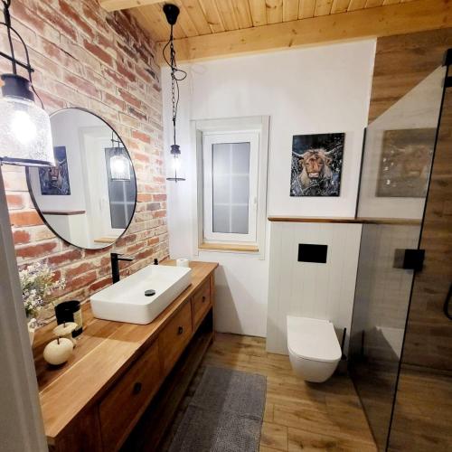 a bathroom with a white sink and a brick wall at Ann-tonówka in Brzózki