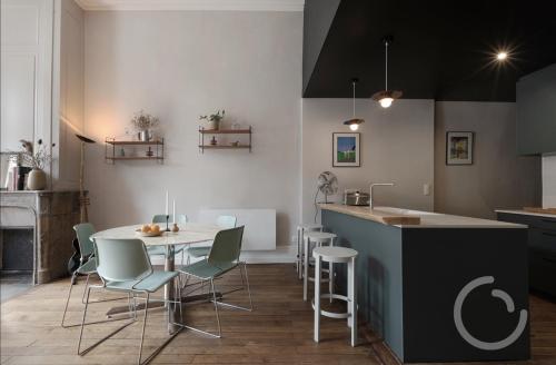 une cuisine avec une table et des chaises dans une pièce dans l'établissement La troussotte, superbe appartement de 110m2 avec terrasse et jardin, à Salins-les-Bains