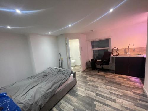 een slaapkamer met een bed, een bureau en een wastafel bij Cosy studio in Queensbury