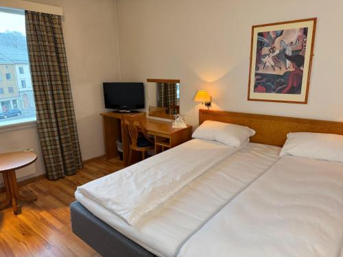 a bedroom with a bed and a desk and a television at Park Hotel Vossevangen in Vossevangen