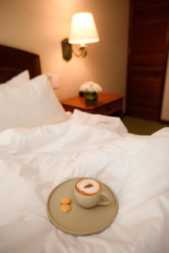 a cup of coffee on a plate on a bed at Los Tallanes Hotel & Suites in Lima