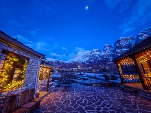 a courtyard with christmas lights on buildings with mountains at Agriogido - Rupicapra Guest Ηouse in Papigko