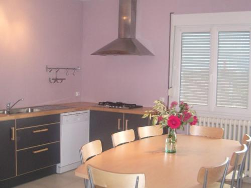 une cuisine avec une table avec un vase de fleurs dessus dans l'établissement Location paisible: gîte familial avec balnéo, cuisine équipée et départs VTT, à proximité de Gérardmer - FR-1-589-331, à Frémifontaine