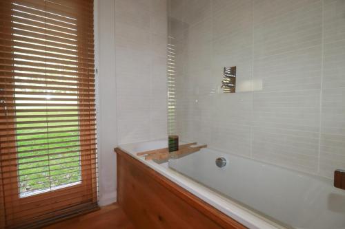 a white bathroom with a tub and a window at 3 Hedgerows in Looe