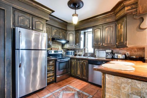 a kitchen with wooden cabinets and a stainless steel refrigerator at Le petit Manoir Spa et Vue sur rivière St Maurice in Grandes-Piles