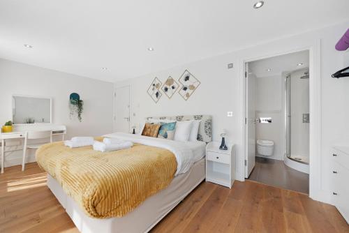 a white bedroom with a large bed with a yellow blanket at Hermitage Road Apartment By Morethanstays in London