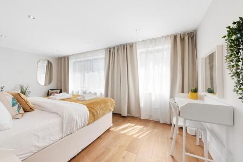 a white bedroom with a bed and a desk at Hermitage Road Apartment By Morethanstays in London