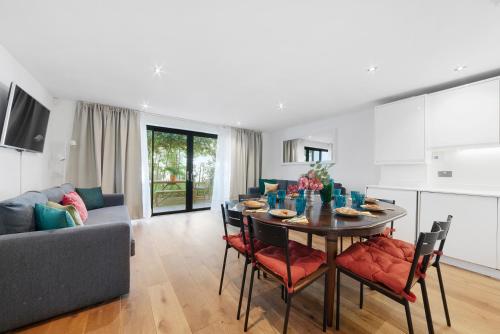 a dining room and living room with a table and chairs at Hermitage Road Apartment By Morethanstays in London