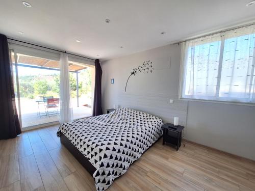 une chambre avec un lit et une grande fenêtre dans l'établissement Association Vita'vie La Villa, à Peyruis