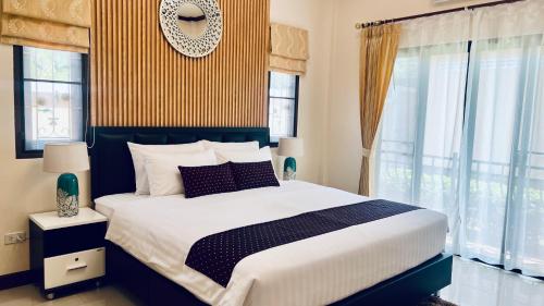 a bedroom with a large bed and windows at Malinee Villa Phuket in Bang Tao Beach
