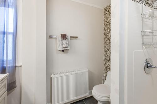 a white bathroom with a toilet and a window at Close to Dtwn Bangor Inviting Maine Home in Veazie