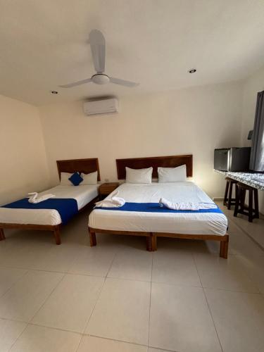 a bedroom with two beds and a ceiling fan at Hotel Rodríguez in Izamal