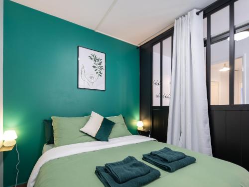 - une chambre verte avec un lit et des serviettes dans l'établissement L'Arlequin Familial et Reposant, à Villeurbanne