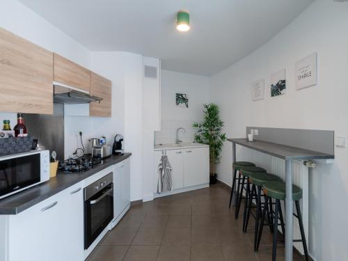 - une cuisine avec des placards blancs et des tabourets de bar dans l'établissement L'Arlequin Familial et Reposant, à Villeurbanne