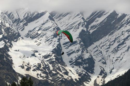 a person flying a kite over a snow covered mountain at Hotel 17 Miles Stone, Manali By Shivaneel Hospitality in Manāli
