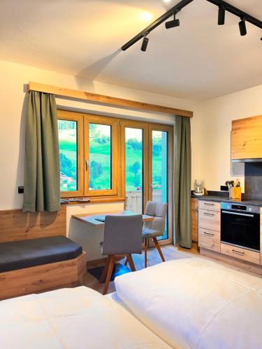 a bedroom with a desk and a kitchen with windows at Schaidreithof in Grossarl