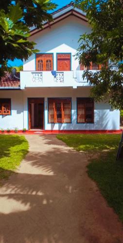 a white house with a pathway in front of it at Dilan Guest in Mirissa