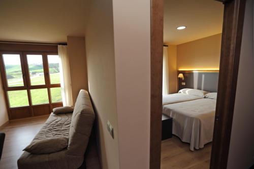 sypialnia z łóżkiem, kanapą i oknem w obiekcie Apartamentos Villa Sofía w mieście San Vicente de la Barquera