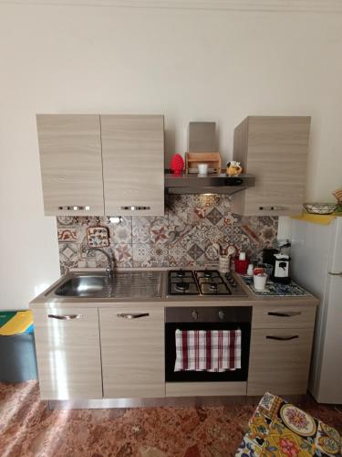 a small kitchen with a stove and a refrigerator at Arco del vescovo 2 in Acireale