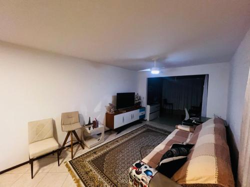 Una sala de estar con un sofá y un televisor. en Apartamento Frente Mar Itapema, en Itapema