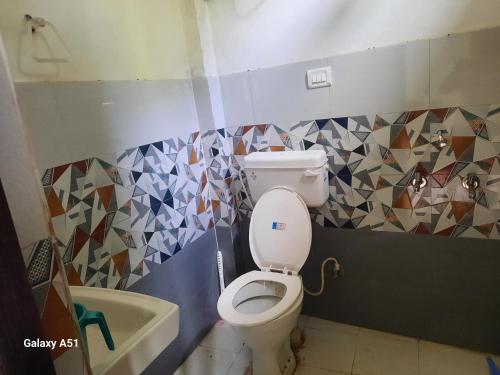a bathroom with a toilet and tiles on the wall at Nature valley home stay in Marchula