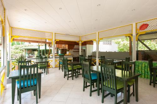 een restaurant met groene stoelen en tafels en ramen bij Pension Michel in La Digue