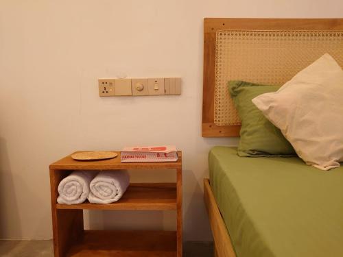 a bed with a night stand with towels on it at Balazo in Ahangama